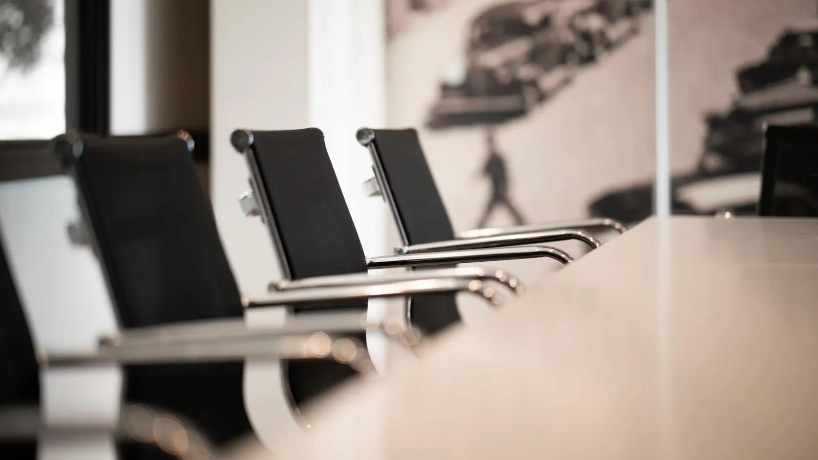Sala de reunião vazia, com mesa longa e cadeiras